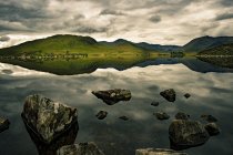 Lago que refleja las tierras altas escocesas - foto de stock
