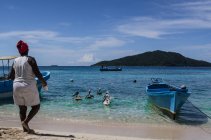 Жінка стоїть на пляжі і годує пеліканів — стокове фото