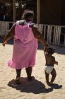 Donna in abito rosa che cammina con il bambino a casa — Foto stock