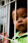 Junge durch Fenstergitter — Stockfoto