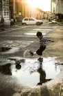 Boy playing soccer in puddle — Stock Photo