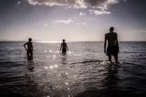 Personas de pie en el agua y mirando el paisaje marino - foto de stock