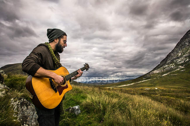 Mann spielt Gitarre im Glencoe Highland — Stockfoto