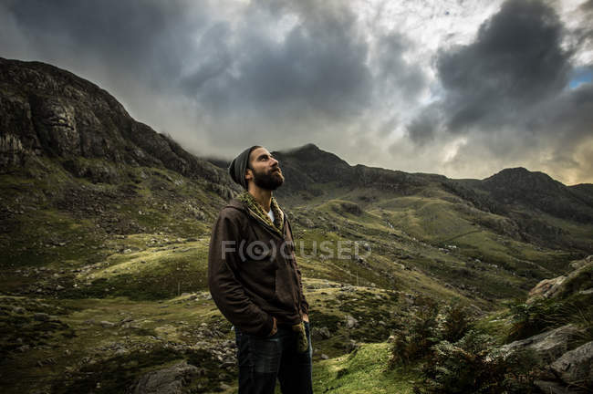 Hombre de pie en las tierras altas y mirando al cielo - foto de stock
