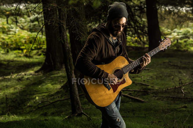 Чоловік грає на акустичній гітарі на лузі — стокове фото