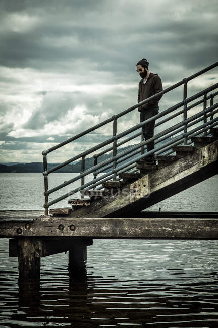 Чоловік стоїть на сходах у пірсі — стокове фото