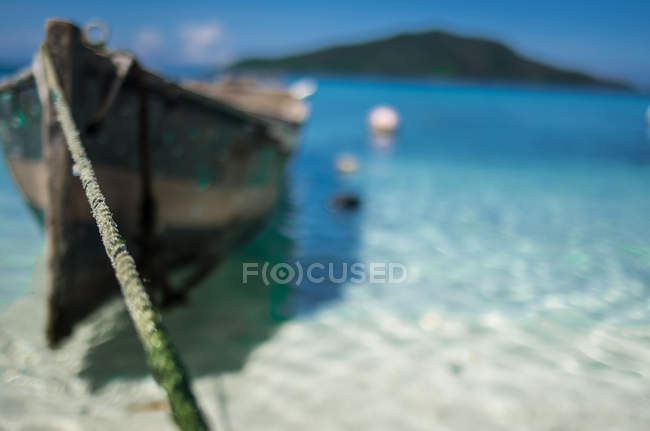 Wooden boat on rope at tropical island — Stock Photo