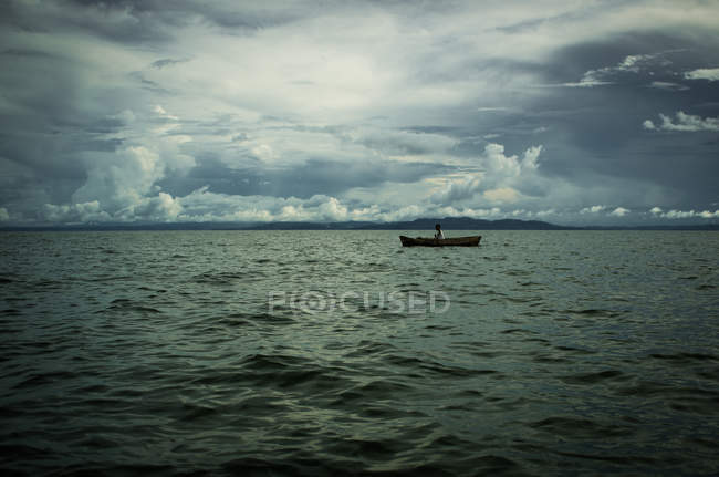 Рыбак в деревянном каноэ на озере — стоковое фото