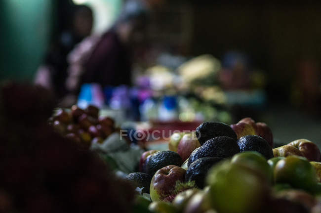 Apples and avocados at indoor market stand — Stock Photo