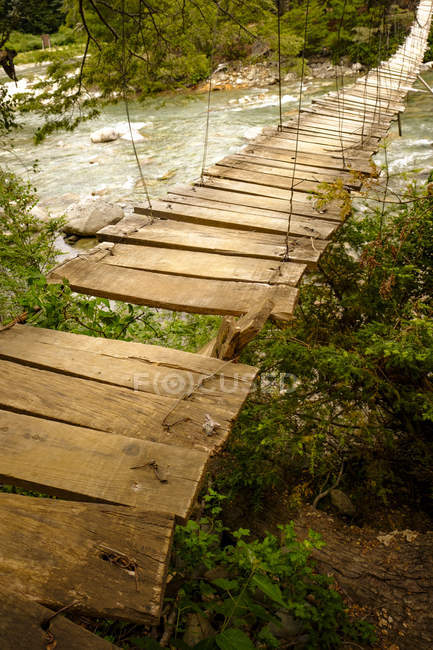 Wooden bridge over mountain river — Stock Photo