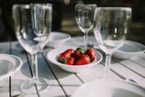 Tisch mit Schüssel mit Erdbeeren in der Mitte — Stockfoto