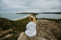 Женщина сидит на скале и смотрит на красивый пейзаж — стоковое фото