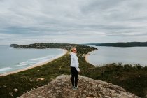 Жінка стоїть на скелі і дивиться на красивий пейзаж — стокове фото