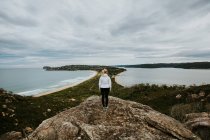 Женщина, стоящая на скале и смотрящая на красивый пейзаж — стоковое фото