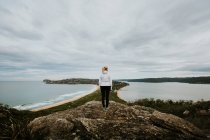 Mujer de pie en la roca y mirando hermoso paisaje - foto de stock