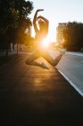 Frau springt in Balletthaltung auf Straße — Stockfoto