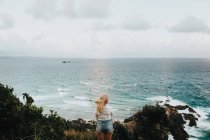 Frau steht auf Fels und blickt auf schöne Landschaft — Stockfoto