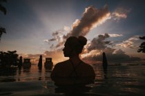 Mujer sentada en el agua y mirando el paisaje marino - foto de stock