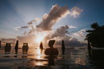 Жінка сидить у воді і дивиться на морський пейзаж — стокове фото