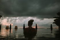 Femme assise dans l'eau et regardant le paysage marin — Photo de stock