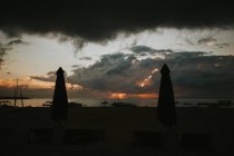 Closed beach umbrellas at sunset — Stock Photo