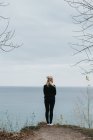 Femme debout sur le rocher et regardant le paysage marin — Photo de stock