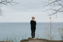 Жінка стоїть на скелі і дивиться на море — стокове фото