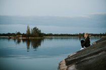 Woman sitting on river shore — Stock Photo