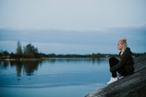 Donna seduta sulla riva del fiume — Foto stock