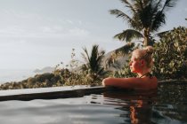 Frau im Pool blickt auf das Meer — Stockfoto