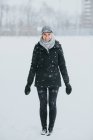 Женщина, стоящая в снежном парке в сельской местности — стоковое фото