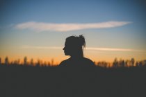 Жінка стоїть в лісі з блакитним небом — стокове фото