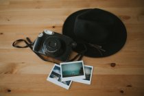 Cámara, fotos instantáneas y sombrero en el escritorio - foto de stock