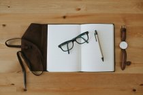 Opened notebook with eyeglasses and pen — Stock Photo