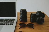 Computer portatile e fotocamera su tavolo — Foto stock