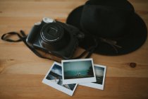Macchina fotografica, foto istantanee e cappello sulla scrivania — Foto stock