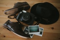 Камера, миттєві фотографії та капелюх на столі — стокове фото