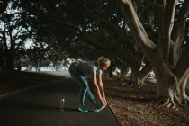 Donna sportiva che si estende nel parco cittadino — Foto stock