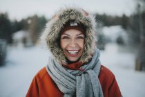 Женщина, стоящая в капюшоне и улыбающаяся в камеру — стоковое фото