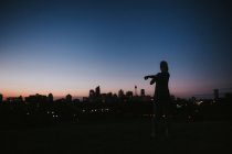 Frau streckt sich gegen Stadt am Horizont — Stockfoto