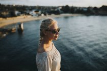 Frau mit Sonnenbrille blickt aufs Meer — Stockfoto