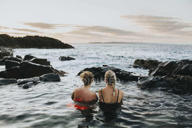 Mulheres sentadas na água e olhando para a paisagem marinha — Fotografia de Stock