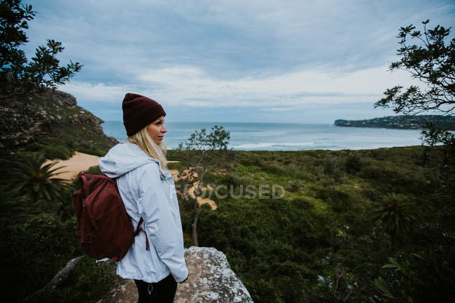 Женщина, стоящая на скале и смотрящая на красивый пейзаж — стоковое фото