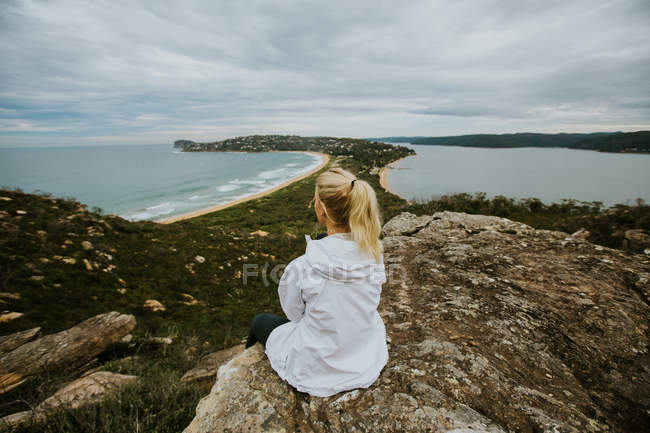 Mulher sentada na rocha e olhando para a bela paisagem — Fotografia de Stock