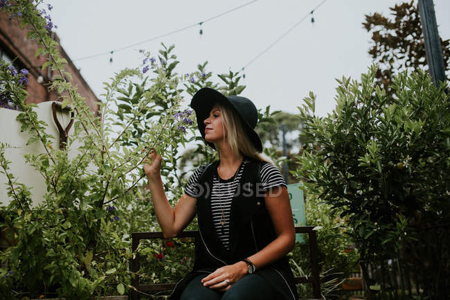 Donna seduta su panchina in giardino — Foto stock