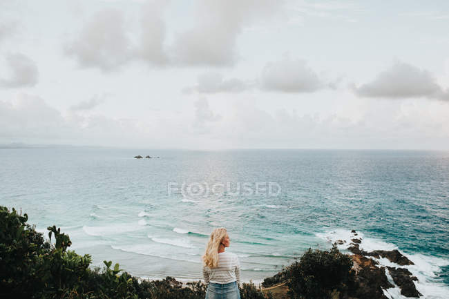 Mulher de pé na rocha e olhando para a bela paisagem — Fotografia de Stock