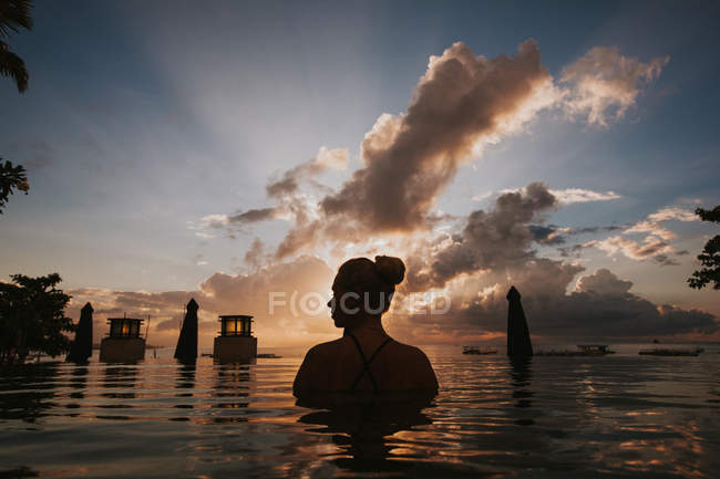 Femme assise dans l'eau et regardant le paysage marin — Photo de stock
