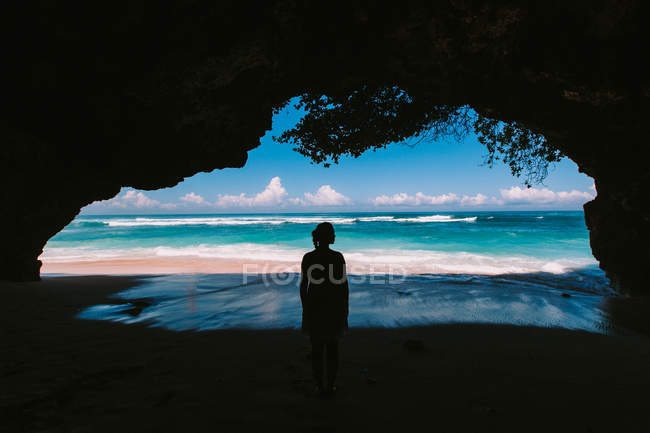 Жінка стоїть в природній печері і дивиться на морський печеру — стокове фото