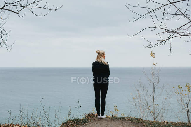 Donna in piedi sulla roccia e guardando il paesaggio marino — Foto stock