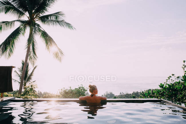 Mulher na piscina olhando para a paisagem marinha — Fotografia de Stock